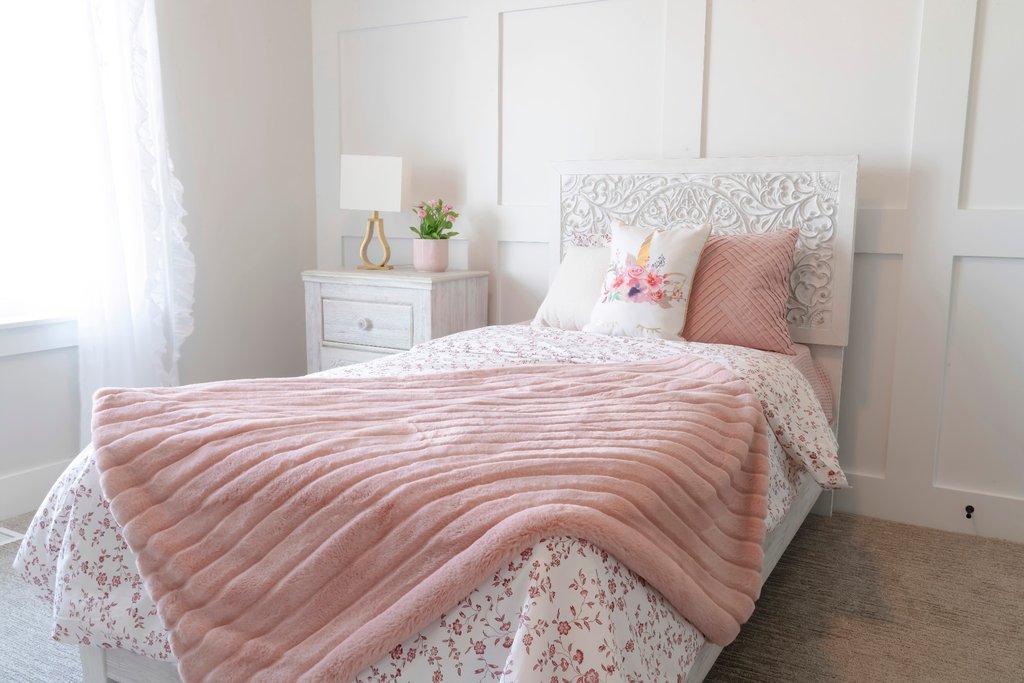 Pink floral bedding with white wainscoting in a cozy bedroom